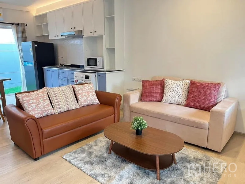 Townhouse for rent in Prawet, Bangkok - Cozy open‑plan living zone with two sofas, coffee table, and adjacent kitchen.