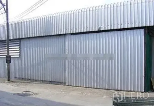 Warehouse for rent in Suan Luang, Bangkok - Street-facing corrugated metal warehouse exterior with wide sliding steel door in Suan Luang, Bangkok.