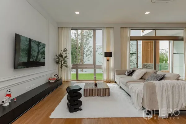 Detached House for rent in Saphan Sung, Bangkok - Bright living room with floor-to-ceiling windows, sofa and garden view.