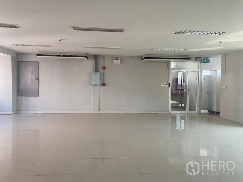 Office Space for rent in Bang Na, Bangkok - Open office area with wall-mounted air-conditioning units, glass entry door and electrical panel.