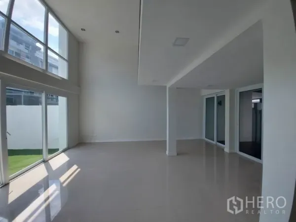 联排别墅 出售在Wang Thonglang, Bangkok - 客厅挑高空间明亮通透，落地窗直通庭院。