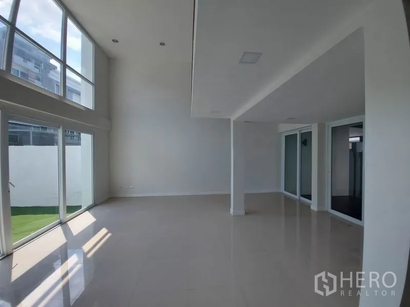联排别墅 出售在Wang Thonglang, Bangkok - 客厅挑高空间明亮通透，落地窗直通庭院。