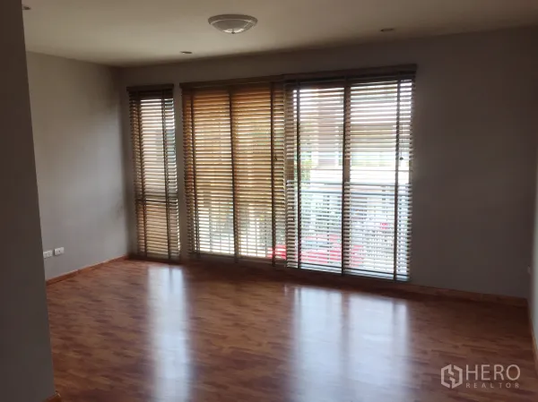Townhouse for rent or sale in Phra Khanong, Bangkok - Bright upper living room with floor-to-ceiling windows and wooden blinds.