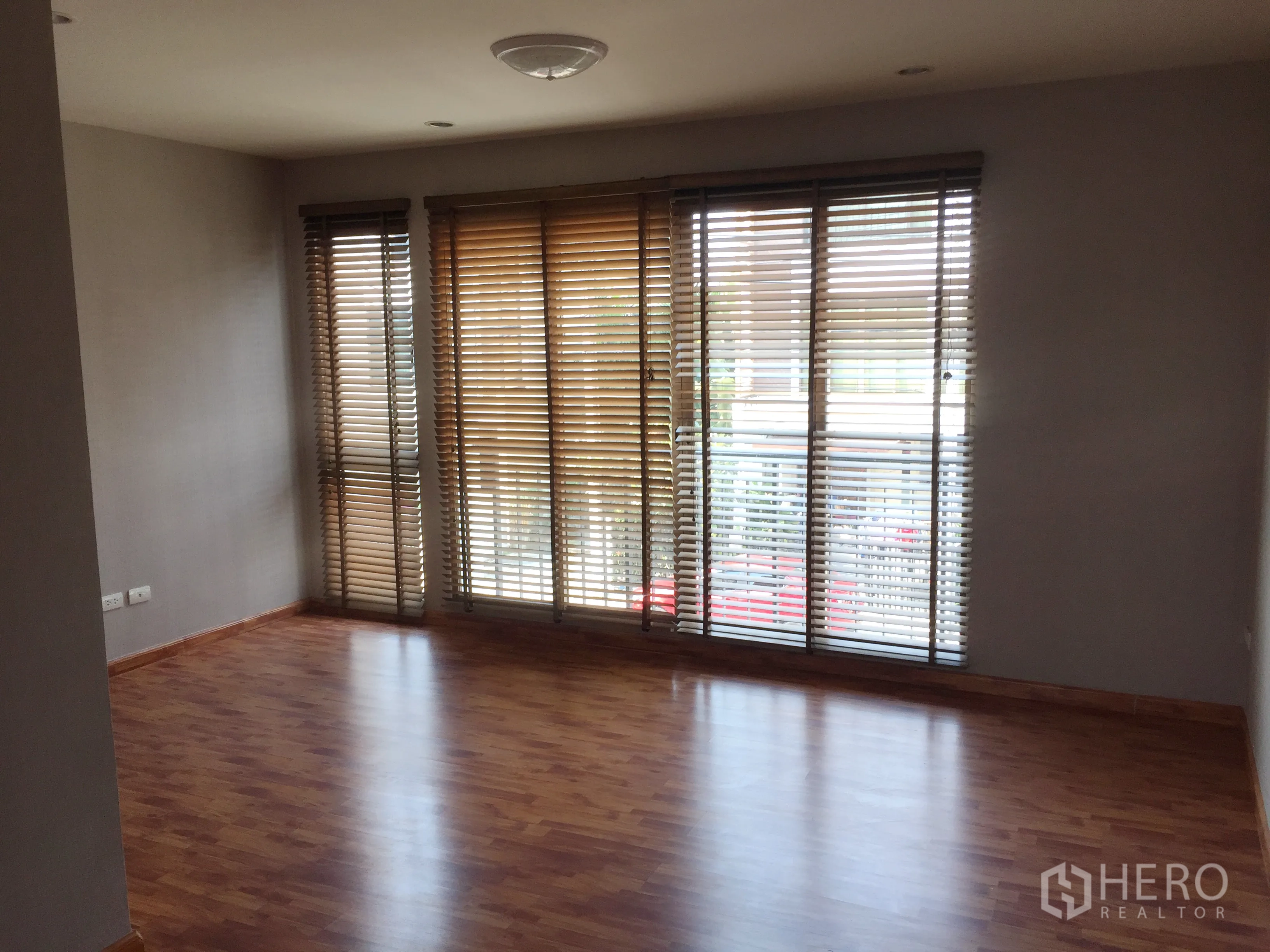 Townhouse for rent or sale in Phra Khanong, Bangkok - Bright upper living room with floor-to-ceiling windows and wooden blinds.