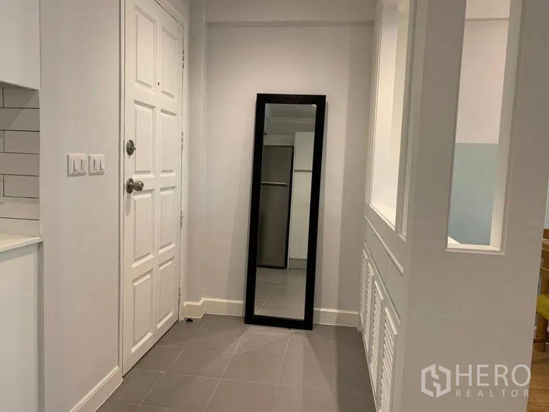 Condominium for sale in Watthana, Bangkok - Entry hallway with gray tile flooring, white door and full-length mirror.