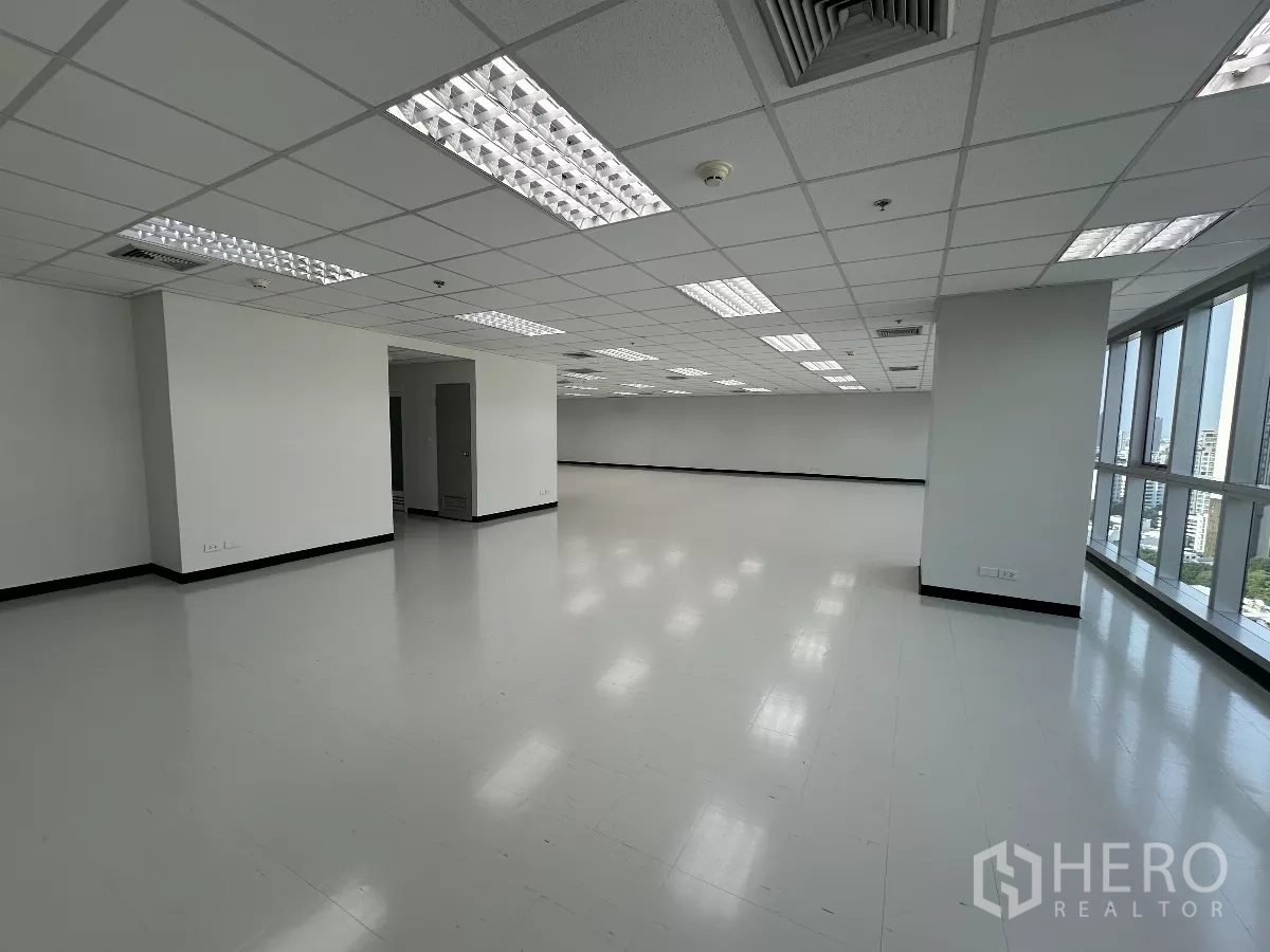 办公空间 出租在Watthana, Bangkok - 转角办公楼层，临窗面宽与立柱，通向服务区的门，自然采光充足。