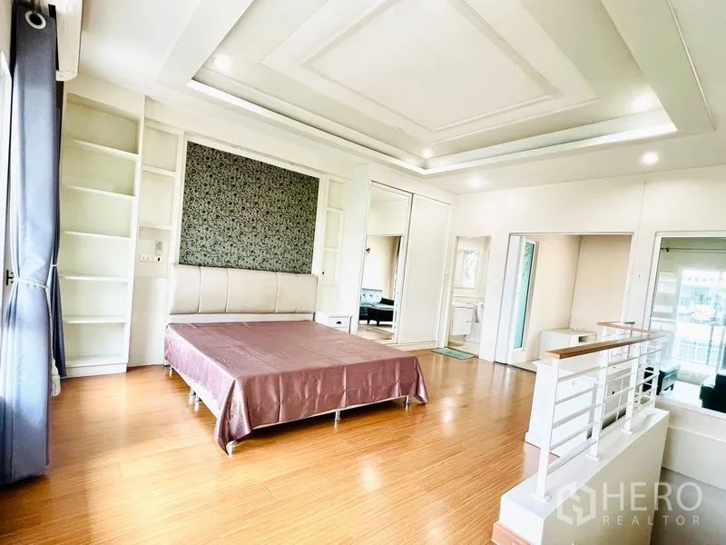 联排别墅 出租在Prawet, Bangkok - 宽大的主卧套间，内置书架、镜面衣柜并连通起居区