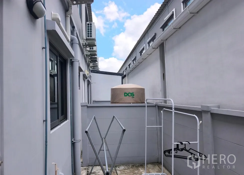 联排别墅 for rent in Bang Phli, Samut Prakan - 侧边家务庭院，蓄水罐、晾衣架与外机排列在墙边。