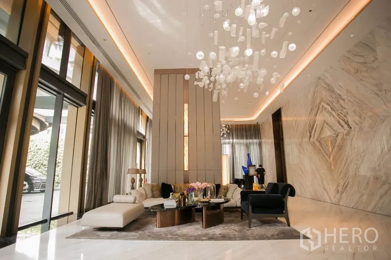 公寓 出租或出售在Watthana, Bangkok - 豪华公寓大堂，石材墙面、挑高天花与水晶吊灯、舒适沙发区。