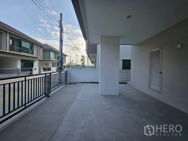 Detached House for rent in Saphan Sung, Bangkok - Covered carport and front patio behind a black metal gate with storage door.