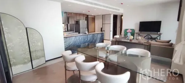 公寓 出租在Watthana, Bangkok - 开放式客餐厅，玻璃餐桌、白色餐椅与蓝纹石岛台的现代厨房。