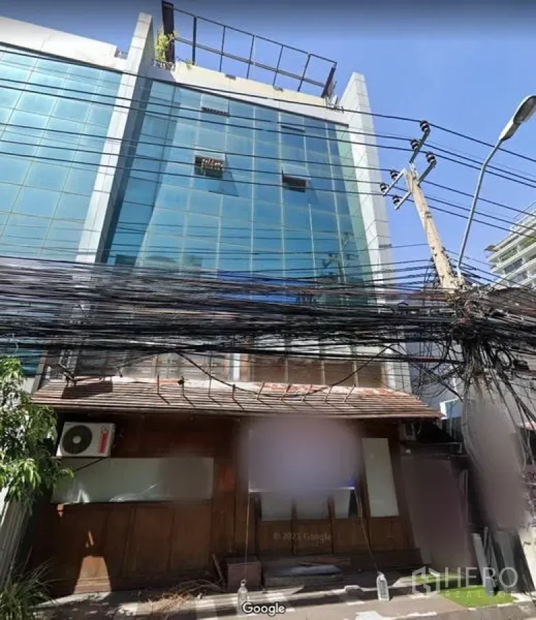 พื้นที่ขายปลีก ให้เช่าในKhlong Toei, Bangkok - ด้านหน้าพื้นที่ค้าปลีกไม้ใต้ตึกกระจกหลายชั้น ในย่านทองหล่อ มีสายไฟและเสาไฟฟ้าด้านหน้า