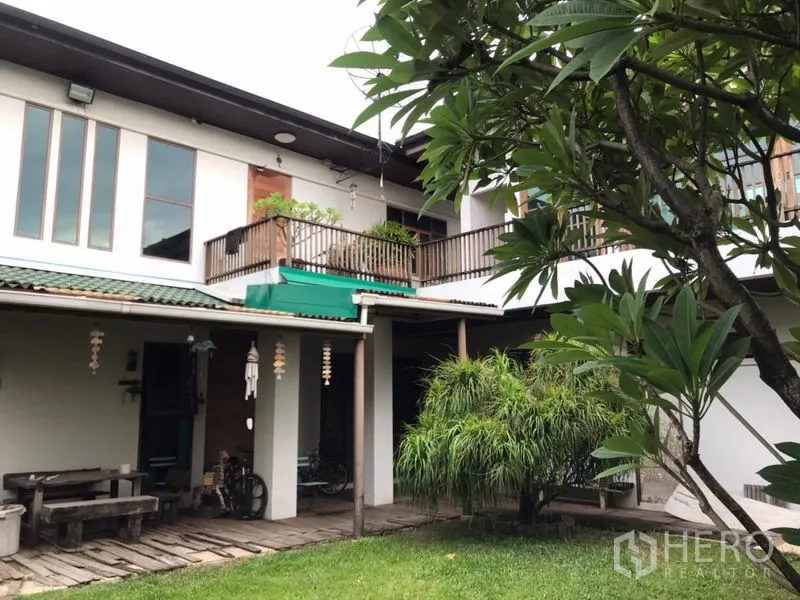 独立式住宅 出售在Lat Phrao, Bangkok - 两层住宅后立面，带阳台、遮蔽露台与景观草坪。