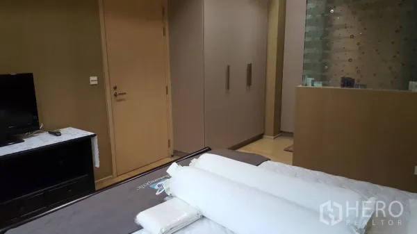 Condominium for rent in Khlong Toei, Bangkok - Bangkok condo bedroom with built-in wardrobe, TV console and frosted glass partition.