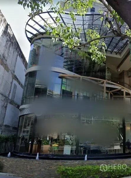 Retail Space for rent in Watthana, Bangkok - Modern retail building with a curved floor-to-ceiling glass facade, canopy, and street-level shopfront in an urban setting.