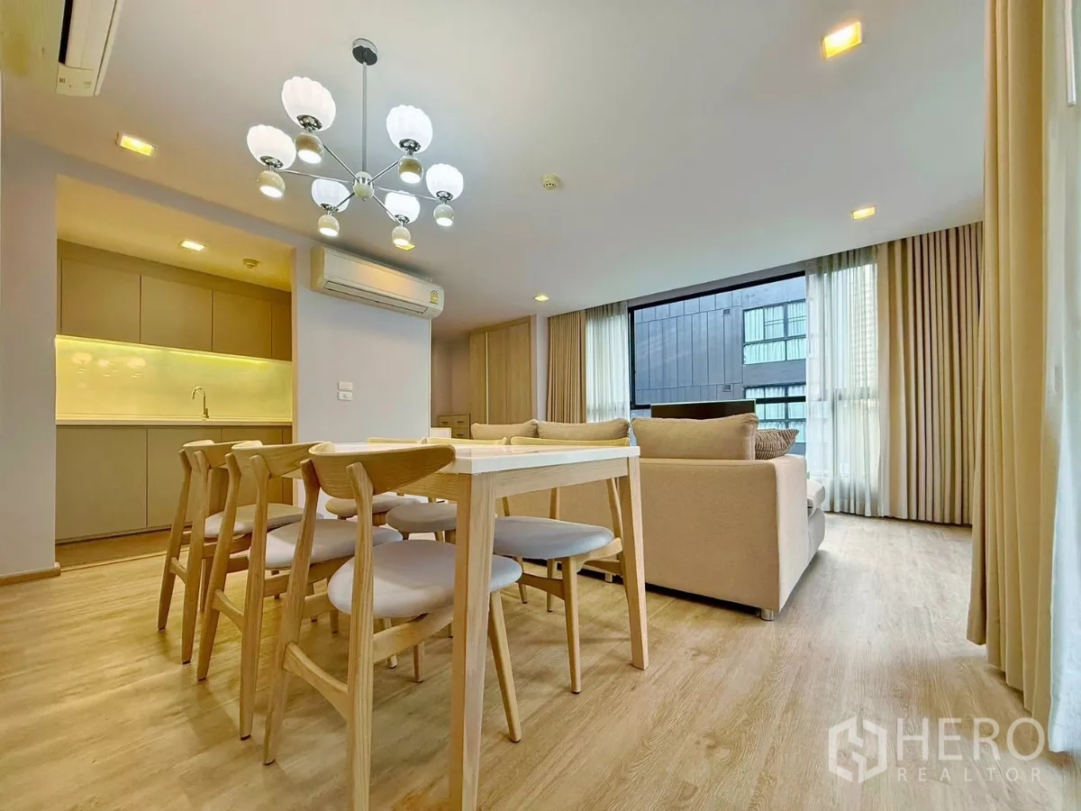 公寓 出租或出售在Watthana, Bangkok - 餐区配六人木餐桌与现代吊灯，旁有窗户。
