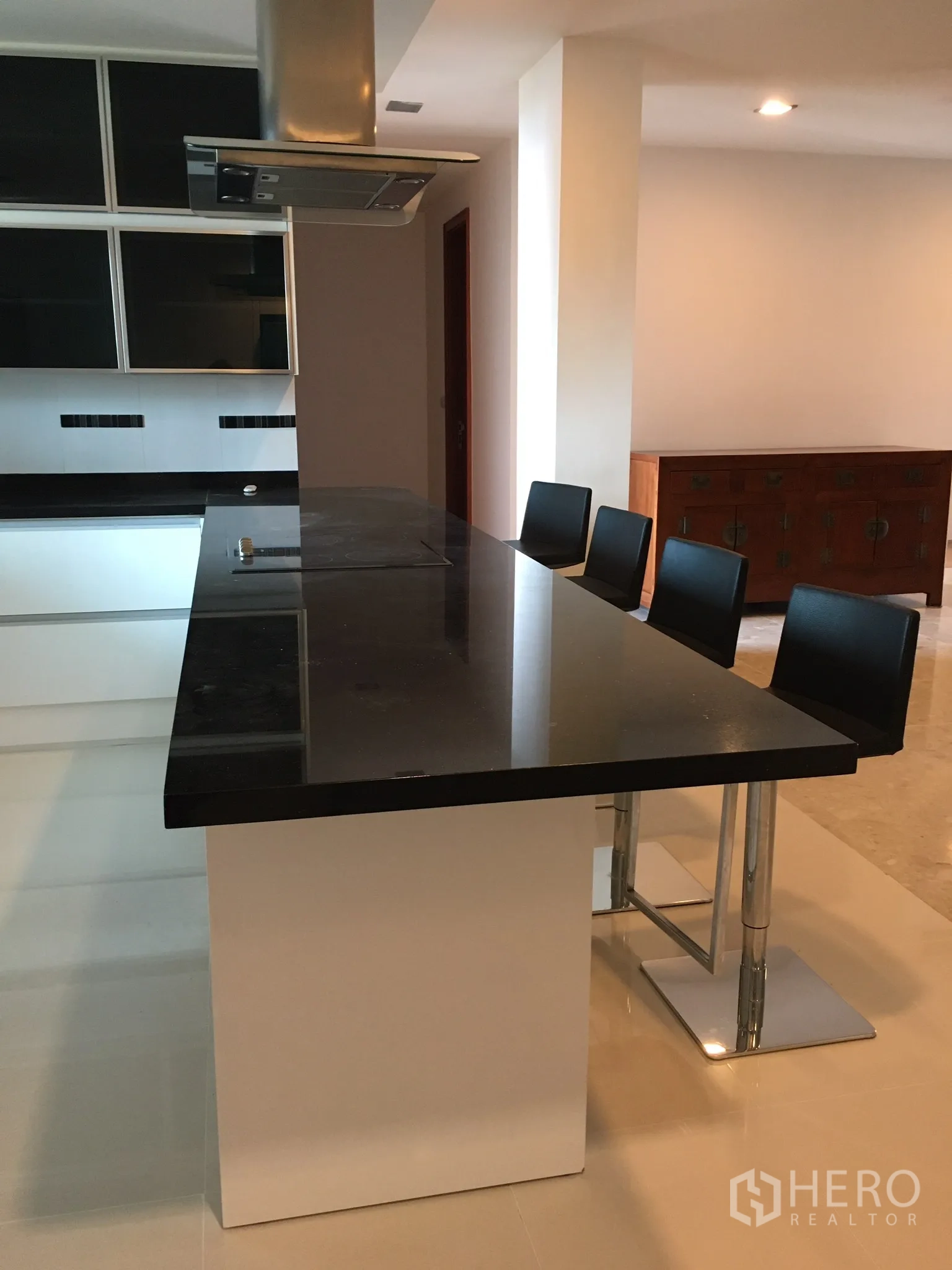 Condominium for rent in Khlong Toei, Bangkok - Close-up of long black countertop island with range hood and bar stools.