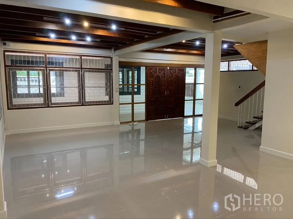 Detached House for rent in Suan Luang, Bangkok - Living room view with staircase, windows, and glossy tiled floor.