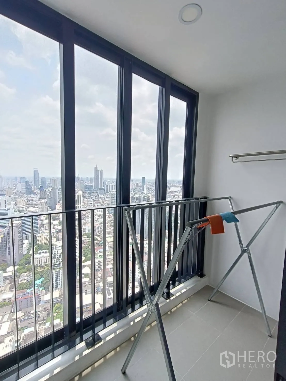 Condominium for rent in Bang Rak, Bangkok - Glass-enclosed balcony or utility area with drying rack and panoramic city view.