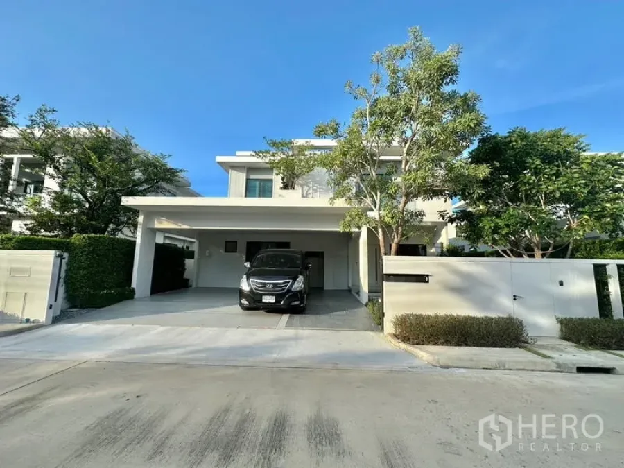 Detached House for rent in Samut Prakan - Street view of a modern detached house with secure wall and wide driveway.