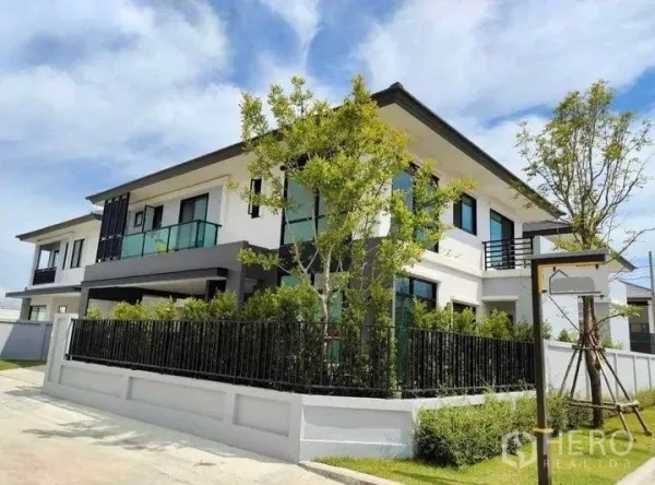 Detached House for rent in Bang Bo, Samut Prakan - Exterior street view of the contemporary two-storey house with landscaped corner garden.