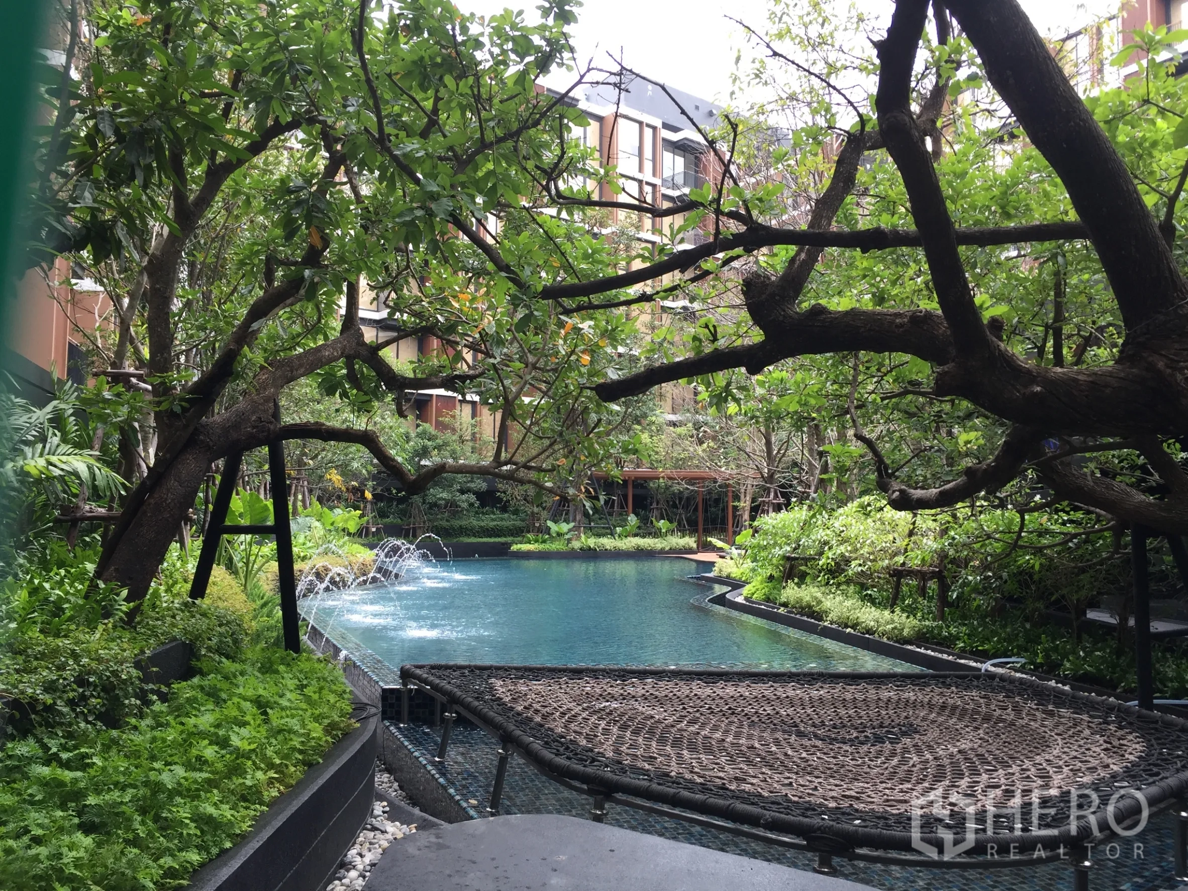 คอนโด ให้เช่าในWatthana, Bangkok - สระว่ายน้ำสไตล์รีสอร์ตท่ามกลางสวนเขียวพร้อมน้ำพุและพื้นที่พักผ่อนแบบตาข่าย.