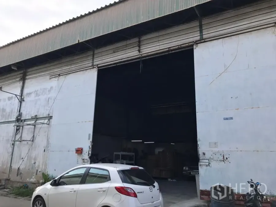 คลังสินค้า ให้เช่าในBang Phli, Samut Prakan - ด้านหน้าโกดังอุตสาหกรรม ประตูเหล็กม้วนกว้าง ทางเข้าหลังคาสูง พร้อมพื้นที่จอดรถด้านหน้า