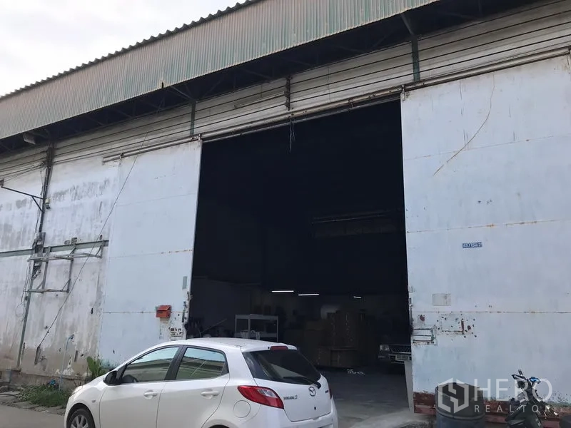 คลังสินค้า ให้เช่าในBang Phli, Samut Prakan - ด้านหน้าโกดังอุตสาหกรรม ประตูเหล็กม้วนกว้าง ทางเข้าหลังคาสูง พร้อมพื้นที่จอดรถด้านหน้า