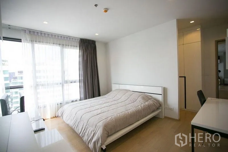 Condominium for rent in Watthana, Bangkok - Spacious bedroom with queen bed, light wood floors and wide window for natural light.
