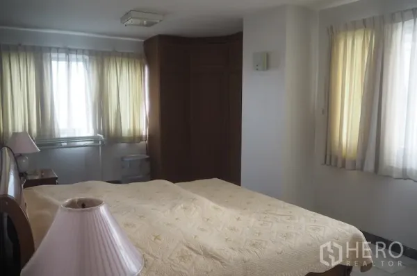 Condominium for rent in Pathum Wan, Bangkok - Sunlit bedroom with large windows, built-in corner wardrobe and a queen bed.