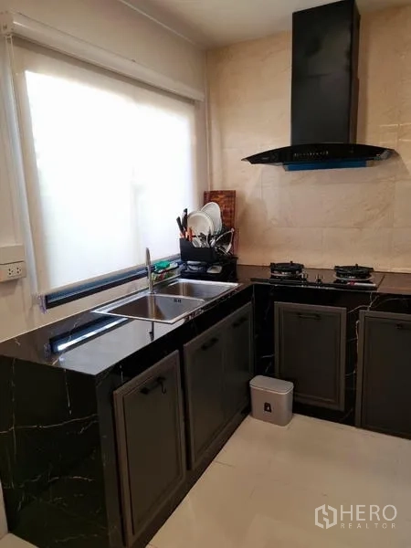 Townhouse for rent - L-shaped kitchen with marble-look countertops, sink, gas hobs and range hood.
