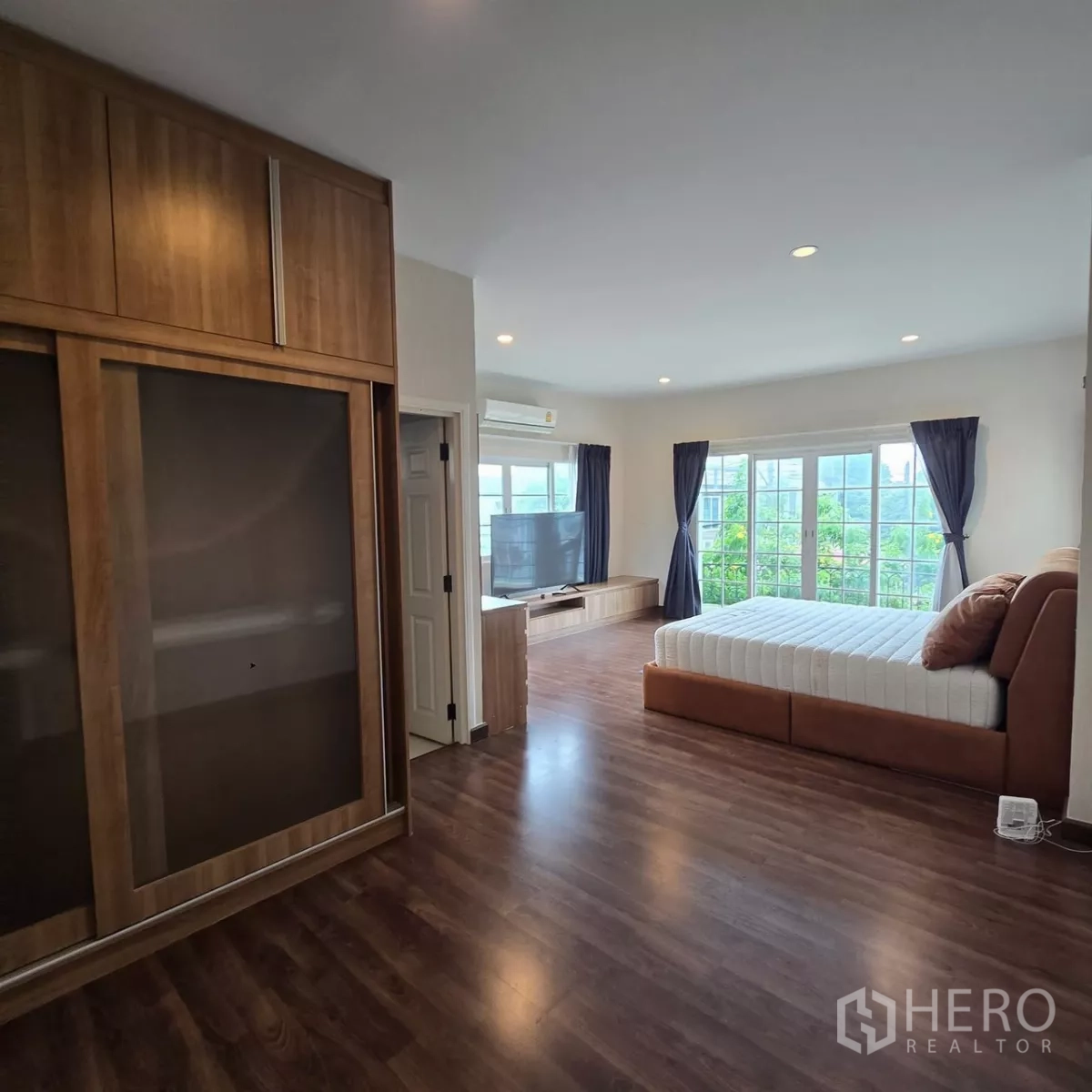 Detached House for rent in Mueang Pathum Thani, Pathum Thani - Spacious bedroom with wood floors, built-in wardrobe and large windows.
