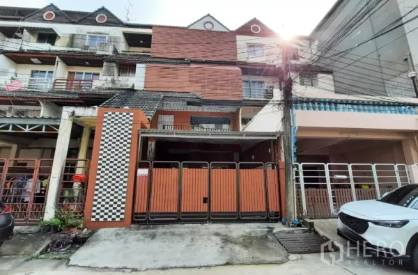 Townhouse for sale in Suan Luang, Bangkok - Front view of the townhouse with folding metal gate and driveway