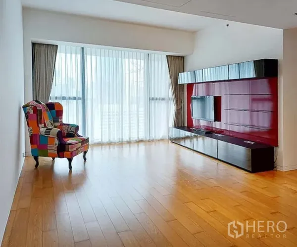 คอนโด ให้เช่าในSathon, Bangkok - ห้องนั่งเล่นสว่าง ผ้าม่านโปร่ง พื้นไม้ ผนังทีวีสีแดงเงา และเก้าอี้ลายแพตช์เวิร์ก