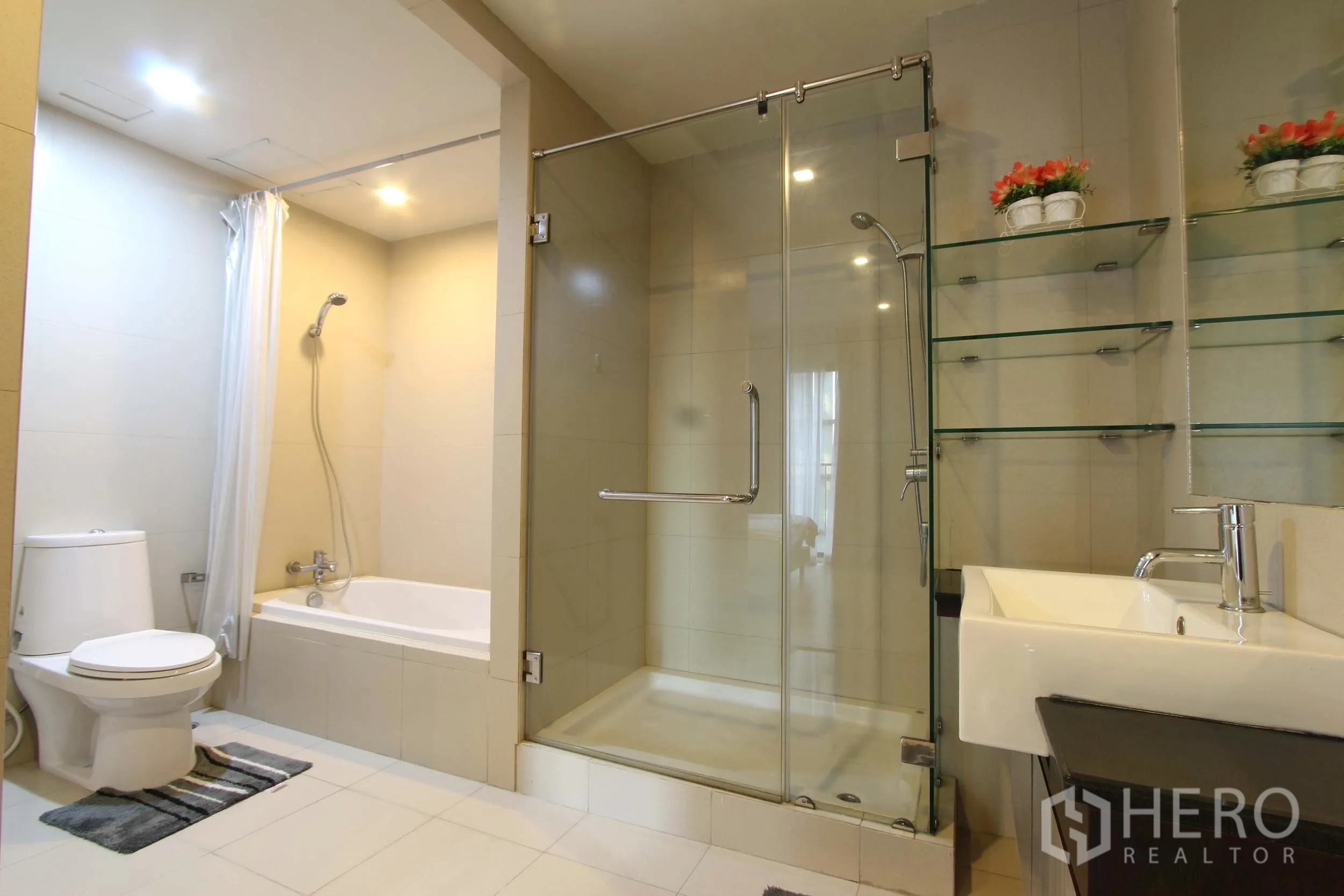 Condominium for rent or sale in Watthana, Bangkok - Bright bathroom featuring a glass-enclosed shower, separate bathtub, toilet and floating sink with glass shelving.