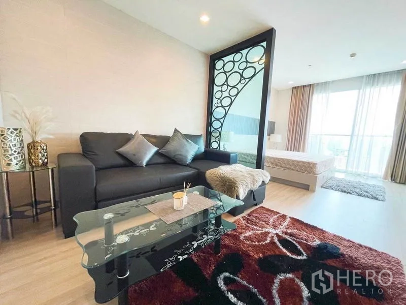 คอนโด ให้เช่าในWatthana, Bangkok - ห้องนั่งเล่นปูพรมลายกราฟิก โต๊ะกระจก ข้างฉากกั้นลวดลายวงกลมแยกส่วนนอน