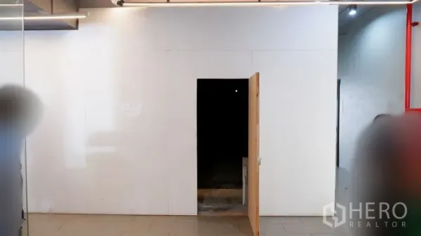 Retail Space for rent in Watthana, Bangkok - White partition frontage with an open wooden door leading into an unfinished indoor retail space.