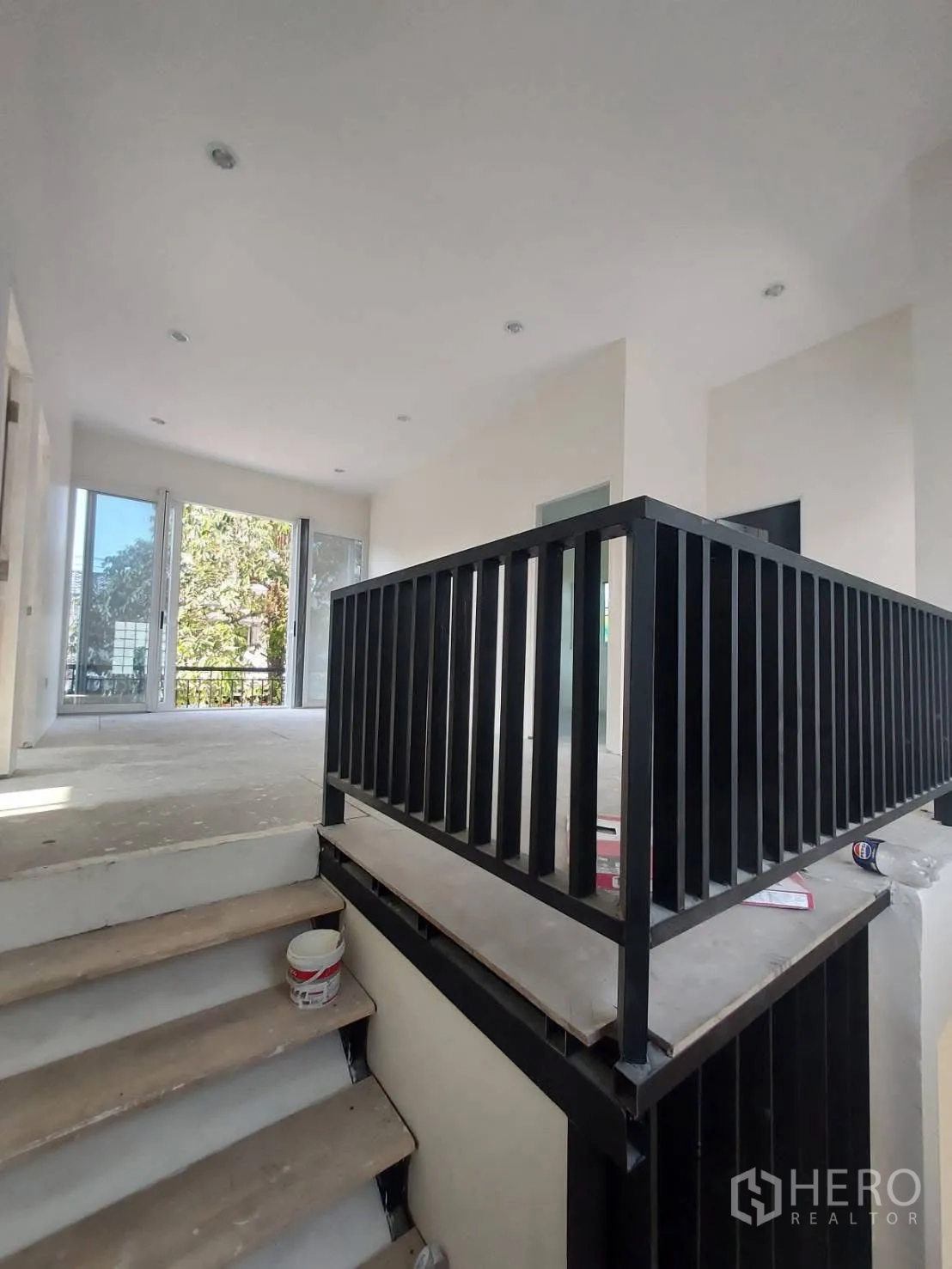 บ้านเดี่ยว for rent in Watthana, Bangkok - บันไดพร้อมราวเหล็กสีดำนำขึ้นสู่โถงชั้นบนที่รับแสงธรรมชาติจากหน้าต่างบานใหญ่.