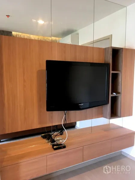 Condominium for rent in Khlong Toei, Bangkok - Mounted TV on wooden panel with floating console and mirrored wall storage