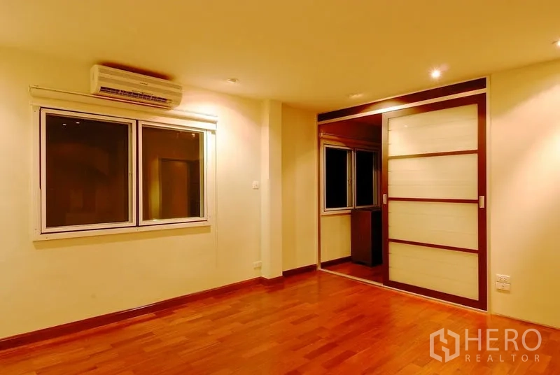 บ้าน ให้เช่าในWatthana, Bangkok - ห้องนอนพื้นไม้ เครื่องปรับอากาศ และประตูบานเลื่อนไปยังตู้เสื้อผ้า