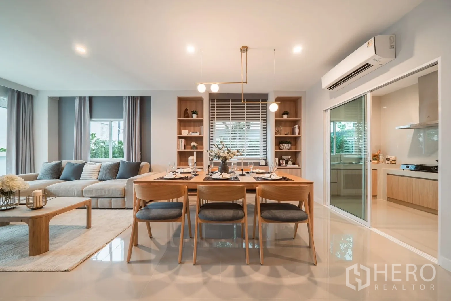Detached House for rent in Saphan Sung, Bangkok - Dining area with wooden table for six, pendant lights and enclosed kitchen behind glass doors.