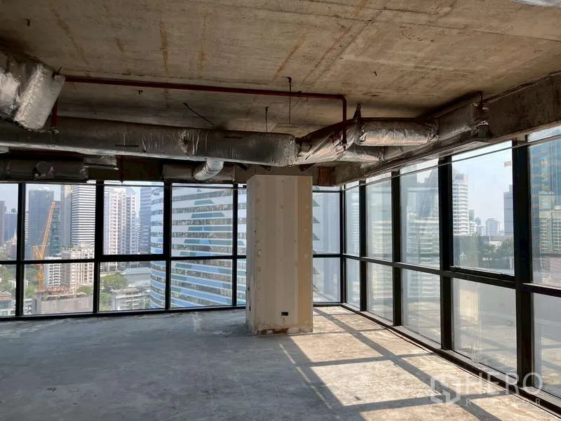 办公空间 出租 - 采光充足的角落毛坯办公室，通高玻璃与水泥天花，可俯瞰城市建筑。