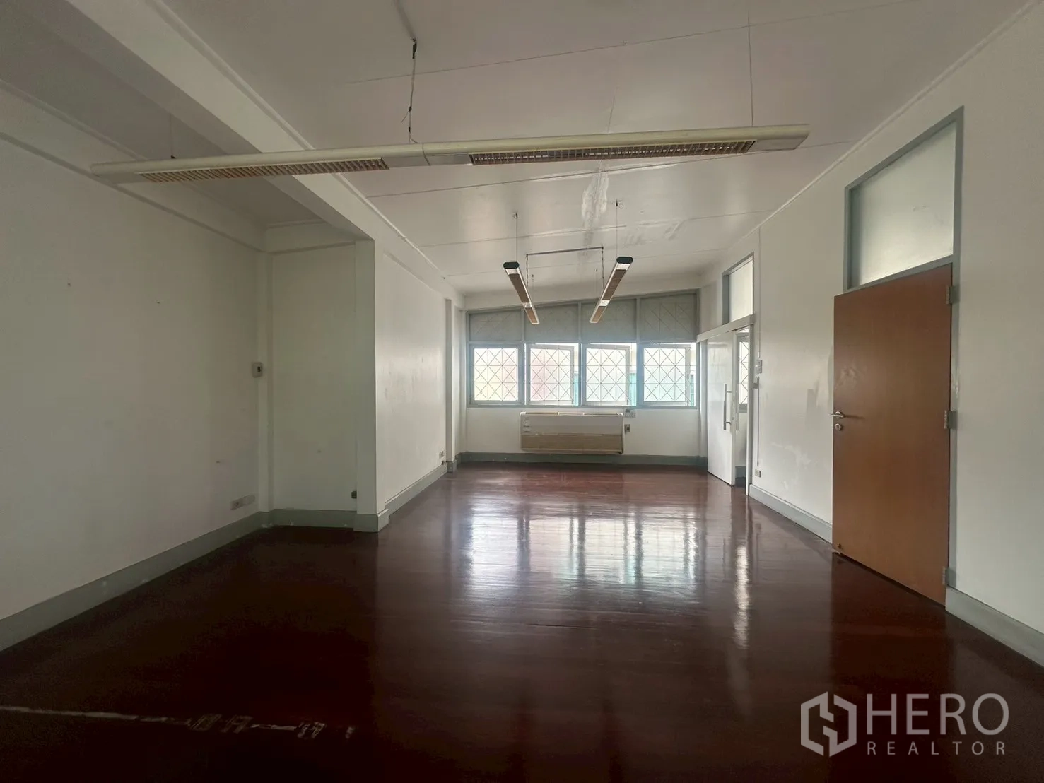 独立式住宅 出租在Watthana, Bangkok - 二楼大房间，深色亮木地板与吊装长条灯。