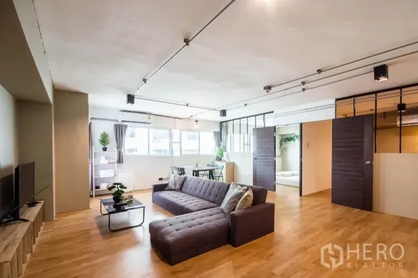 Home Office for rent in Phaya Thai, Bangkok - Spacious open-plan living and office area with sectional sofa, dining set and large windows.