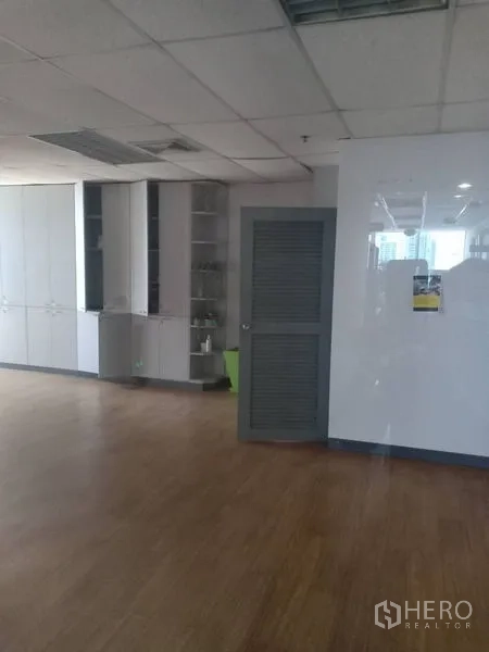 Office Space for rent - Corner of office showing tall storage cabinets, louvered door, large window and wood flooring.