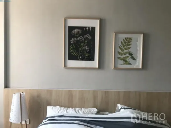 公寓 出租在Watthana, Bangkok - 极简卧室，浅木色床头与植物艺术画，灰色墙面清新舒适。