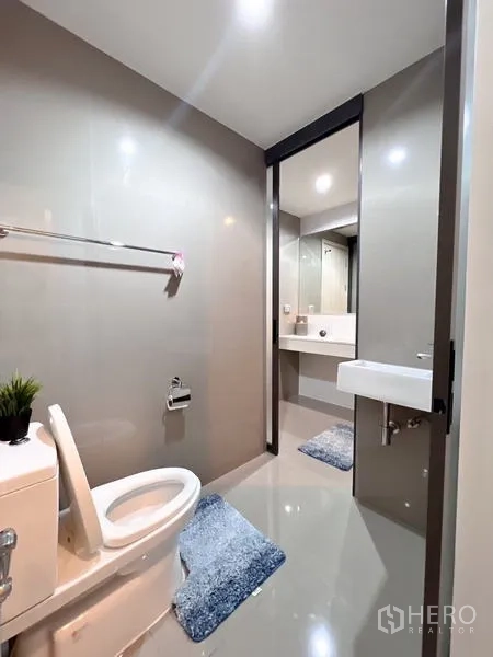 Condominium for rent or sale in Khlong Toei, Bangkok - Separate toilet area with small sink, towel bar and gray tiled walls.