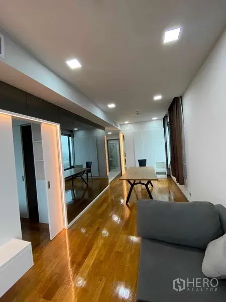 Condominium for rent or sale in Khlong Toei, Bangkok - Spacious living room with sofa, dining table, polished floors and minimalist built-ins.