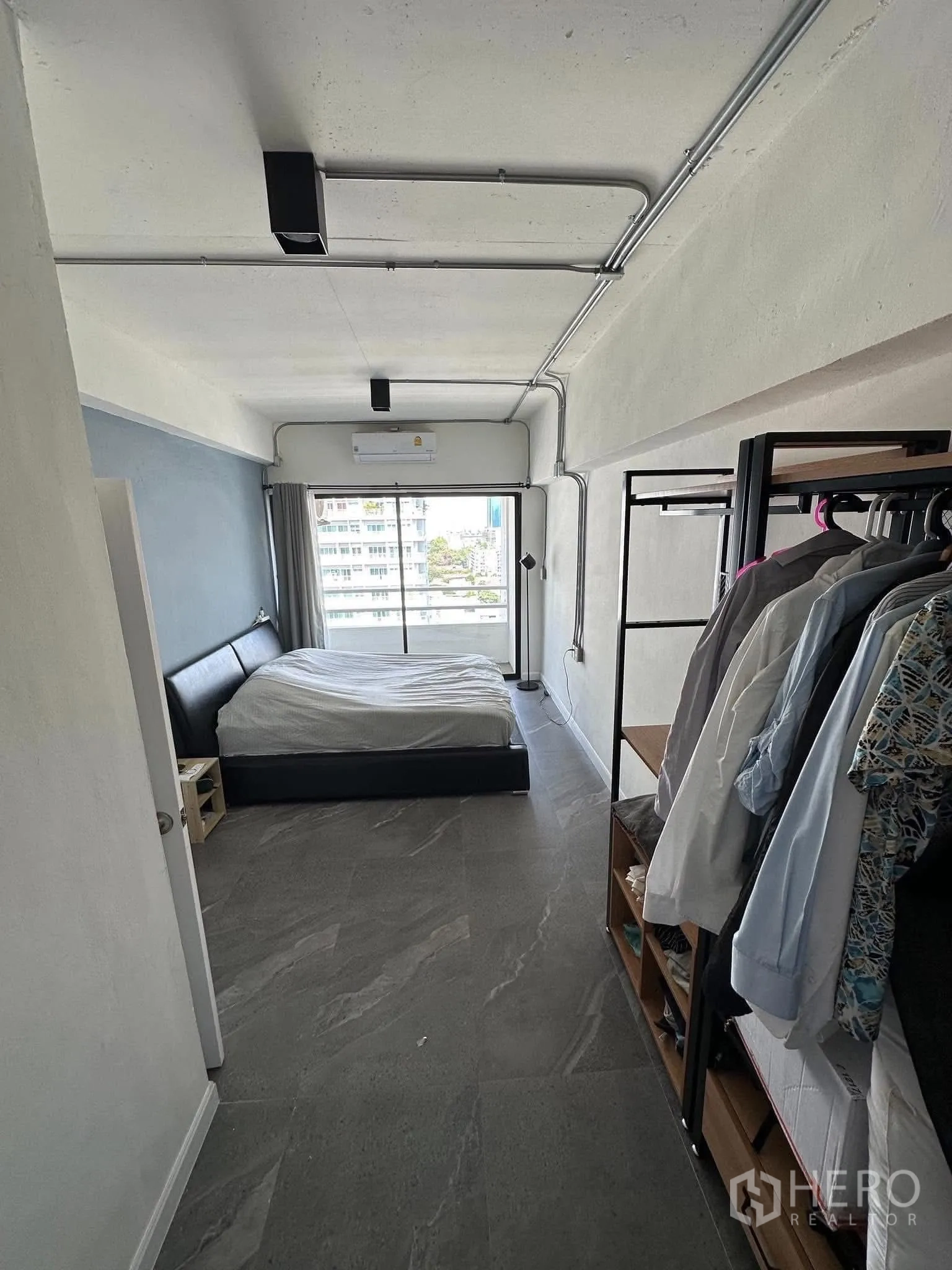 公寓 出租在Watthana, Bangkok - 狭长主卧，开放式衣架与灰色地砖，尽头通阳台。