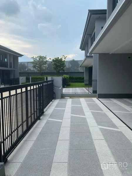 Detached House for rent or sale in Bang Kapi, Bangkok - Side terrace and walkway leading to the front gate with metal fence.